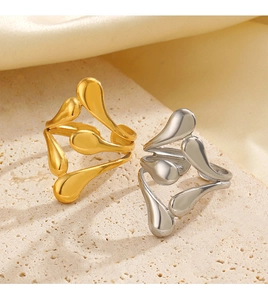 Detail of stacked gold and silver fluid wave rings on natural stone texture