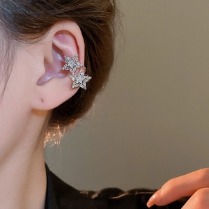 Close-up of sparkling silver star ear cuffs with cubic zirconia on a model's ear