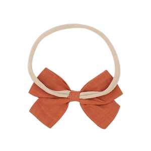 Minimalist soft nylon baby headband with a vibrant orange-red fabric bow on white background