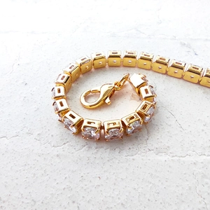 Macro shot of gold tennis bracelet with round cubic zirconia and lobster clasp