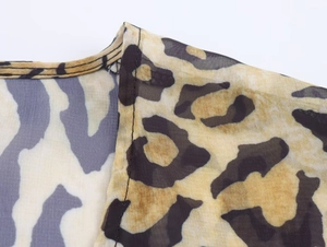 Detailed macro view of deep V-neck stitching and sheer leopard print chiffon fabric