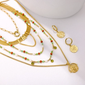 Detail of layered gold necklace with green beads and vintage coin pendant