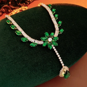 Detail of floral zircon necklace with green gemstones on green velvet padding