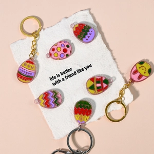 Colorful Easter egg resin keychains with wave patterns on decorative paper background