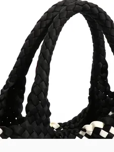 Detailed macro view of black and white hand-woven tote bag showing intricate craft texture