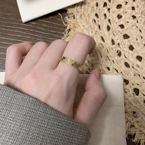 Macro shot of gold-plated titanium ring with dragon scale texture on model's finger
