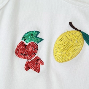 Women's white cropped tank top featuring vibrant fruit sequin embroidery and knit texture