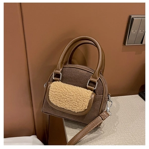 Detail of brown plush tote bag with white shearling trim and metallic hardware