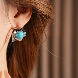 Detail of vintage round turquoise earring with silver textured base on model