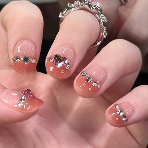 Detailed close-up of pink gradient cat-eye press-on nails with heart rhinestones