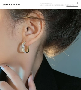Macro shot of a U-shaped gold earring with pave set zircons worn on ear lobe