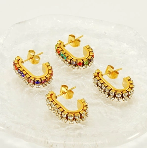 Macro view of gold-plated C-shaped stainless steel earrings with colorful rhinestones