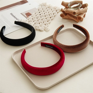 Thick velvet headband set in black, burgundy and brown on a minimalist beige tray