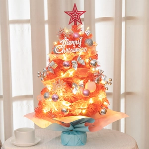 Detailed view of mini Christmas tree with warm lights and festive golden ornaments