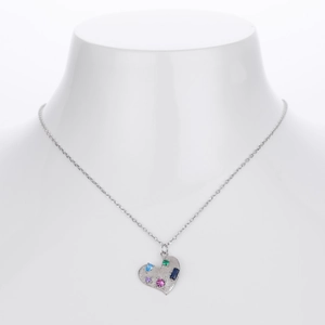 Close-up of heart-shaped silver necklace with brushed texture and colorful gemstones