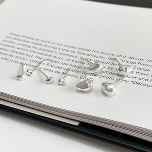 Close-up of pebble-shaped 925 sterling silver earrings on an artistic book background