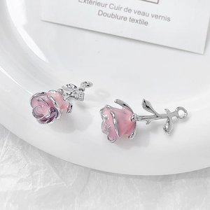 Macro view of pink enamel rose pendants with silver leaves for jewelry making