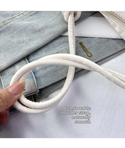 Detail of white round leather strap and light blue denim fabric with yellow stitching