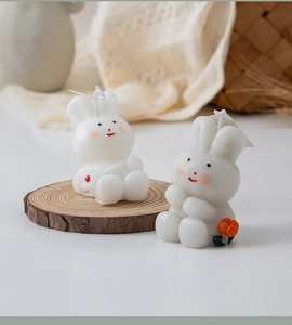 Detail view of a white bunny-shaped candle on a wooden coaster for home decoration