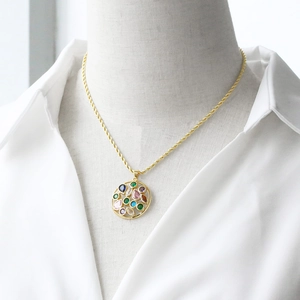 Gold rope chain necklace with a circular cutout pendant featuring multi-color gemstones