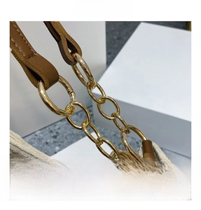 Detailed close-up of golden metal chain strap and brown leather accents on a suede tote
