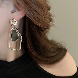 Close-up of geometric asymmetric silver earrings with irregular textured details