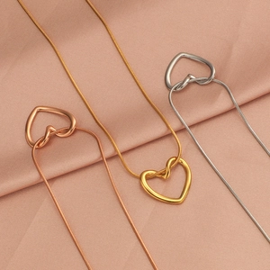 Detailed shot of heart pendants in gold, silver, and rose gold on pink satin fabric