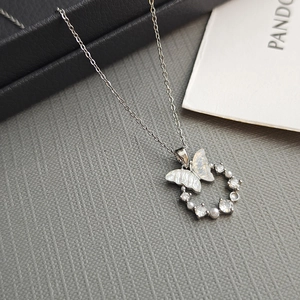 Detailed close-up of a silver butterfly pendant with mother of pearl and pearls