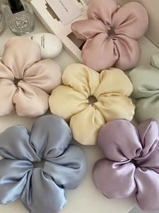 Close-up of assorted satin floral scrunchies in pastel colors on a white surface