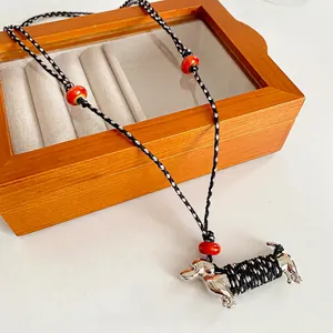 Minimalist cotton woven necklace with creative ceramic dachshund dog pendant on wood box