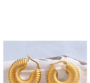 Detailed macro view of golden croissant-style earrings with grooved spiral texture