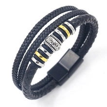 Detail of multi-layer black braided leather bracelet with silver skull bead and magnetic clasp