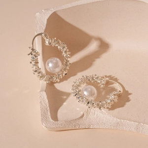 Boucles d'oreilles créoles argentées texturées avec perle blanche sur support en pierre