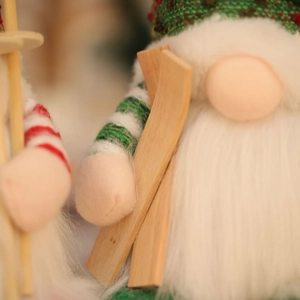 Macro shot of knitted Christmas gnome featuring striped patterns and wooden ski detail