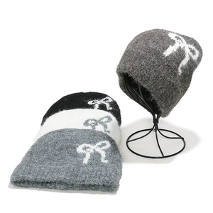 Cozy women's knitted beanie set with bow pattern in black, white, and grey colors