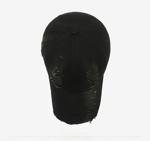 Top view of a black distressed baseball cap with vintage ripped details and cotton texture