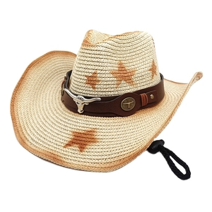 Detailed view of beige straw cowboy hat with star pattern and bull head leather band