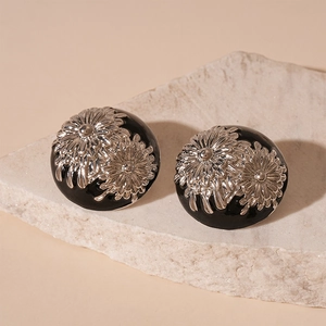Macro detail of round vintage black enamel earrings with silver daisy floral relief