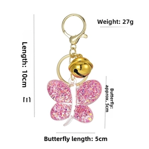 Detailed view of pink glitter acrylic butterfly keychain with gold bell and lobster clasp