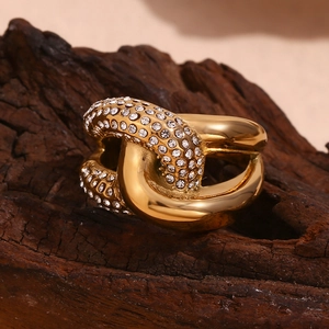 Macro shot of 18K gold plated knotted ring with pavé-set cubic zirconia on dark wood