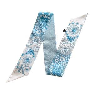 Detail showing floral print pattern and artistic letter K on a blue silk scarf