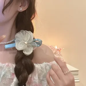 Elegant mesh flower hair clip with pearls and ribbon petals on a braided hairstyle