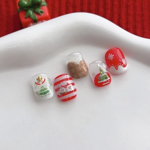 Christmas press-on nails with gingerbread man and snowflake designs on white plate