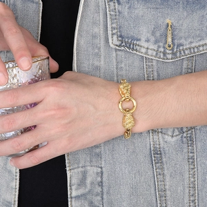 Vue détaillée d'un bracelet tête de lion doré pour homme porté avec une veste en jean