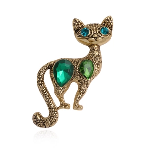 Broche chat dorée vintage avec pierres précieuses vertes sur fond blanc pur