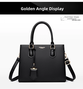 Close-up of black lychee grain leather handbag with gold hardware and logo detail