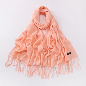Detailed macro view of coral pink scarf with tassels and Classic Scarf woven label