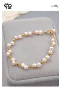 Close-up of handmade freshwater pearl bracelet with gold beads and lobster clasp on velvet