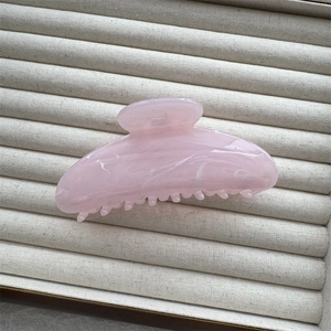 Detail showing pink ink-painted marble resin hair claw clip texture and teeth