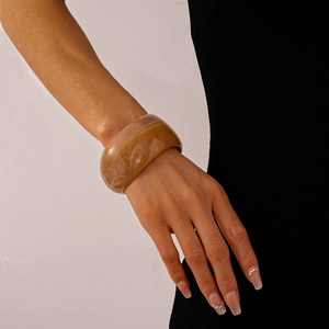 Macro shot of wide marble patterned acrylic bangle with amber swirl textures